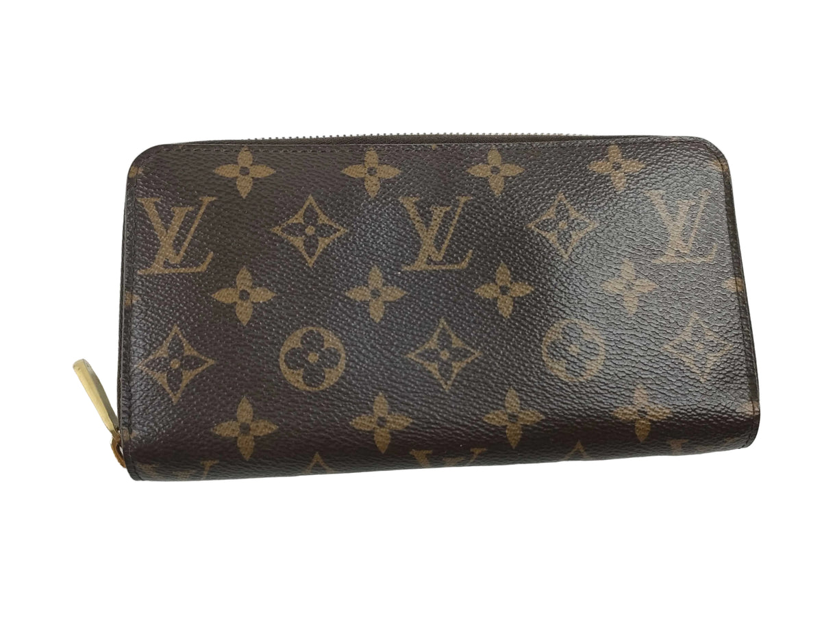 A Louis Vuitton monogram zip-around wallet in brown coated canvas with tan monogram motifs and a gold-tone zipper pull, shown on a plain light background.
