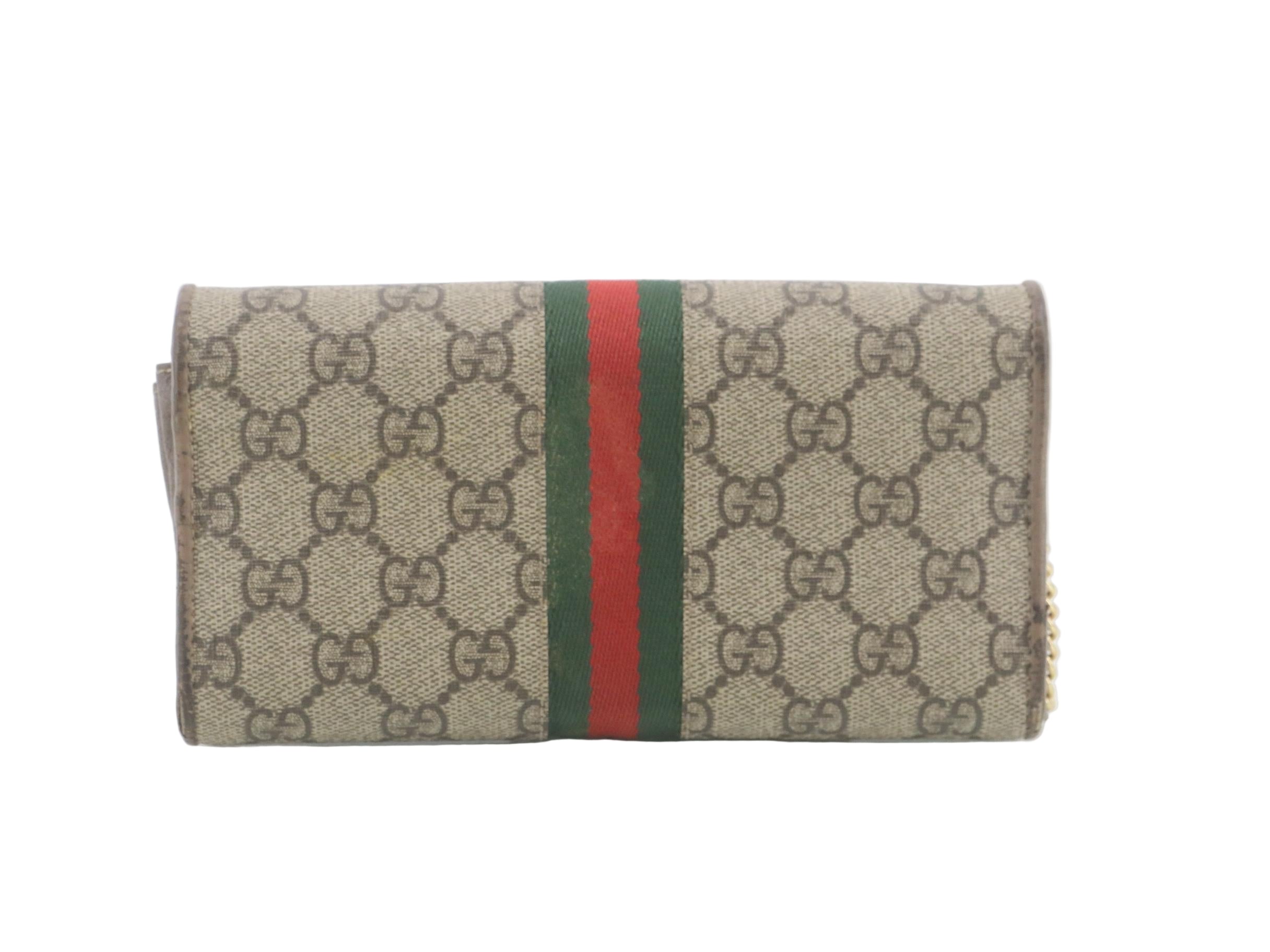 Gucci wallet with monogram pattern and red and green stripe on a white background
