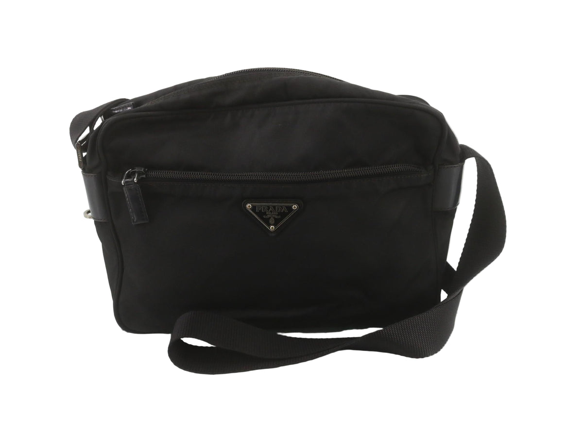 Black nylon Prada bag on a white wooden floor