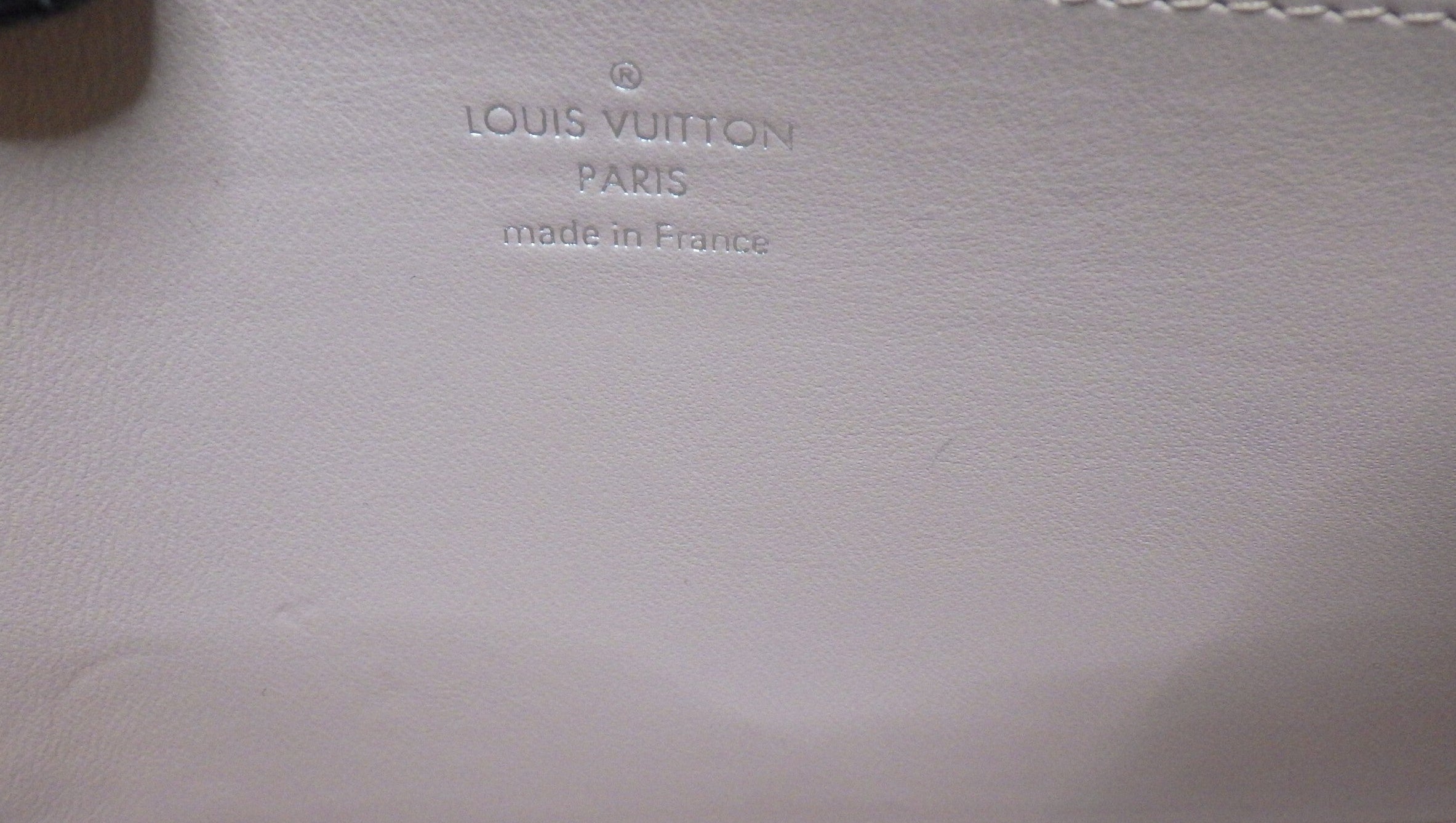 Louis Vuitton logo on a beige leather surface