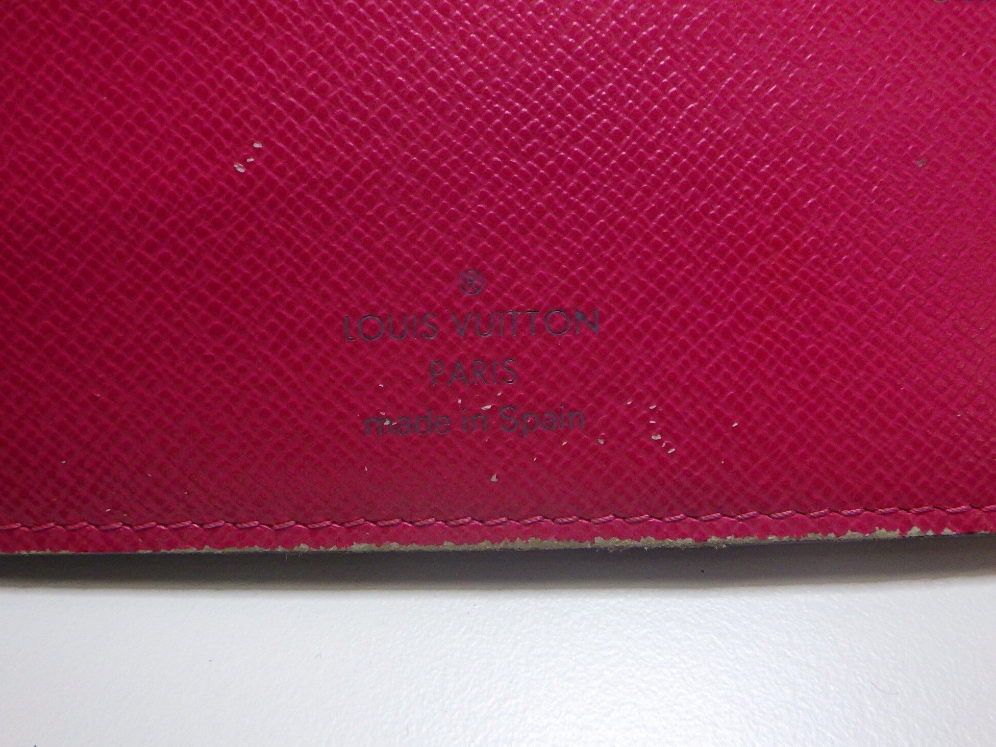 Close-up of a red Louis Vuitton wallet with visible branding.